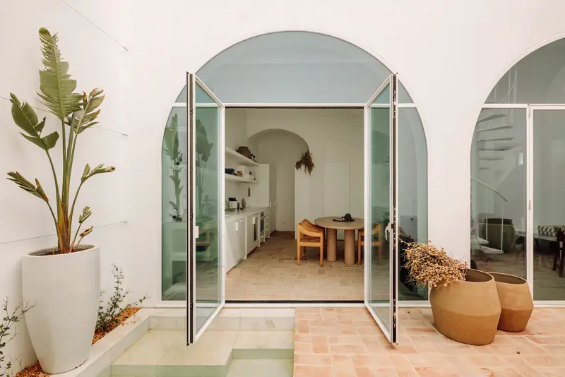 Puertas de acero en arco abiertas hacia un patio con plantas
